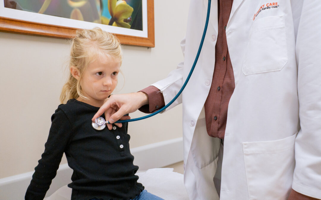 A medical professional listens to the heart of a young girl during an examination at AFC Urgent Care.