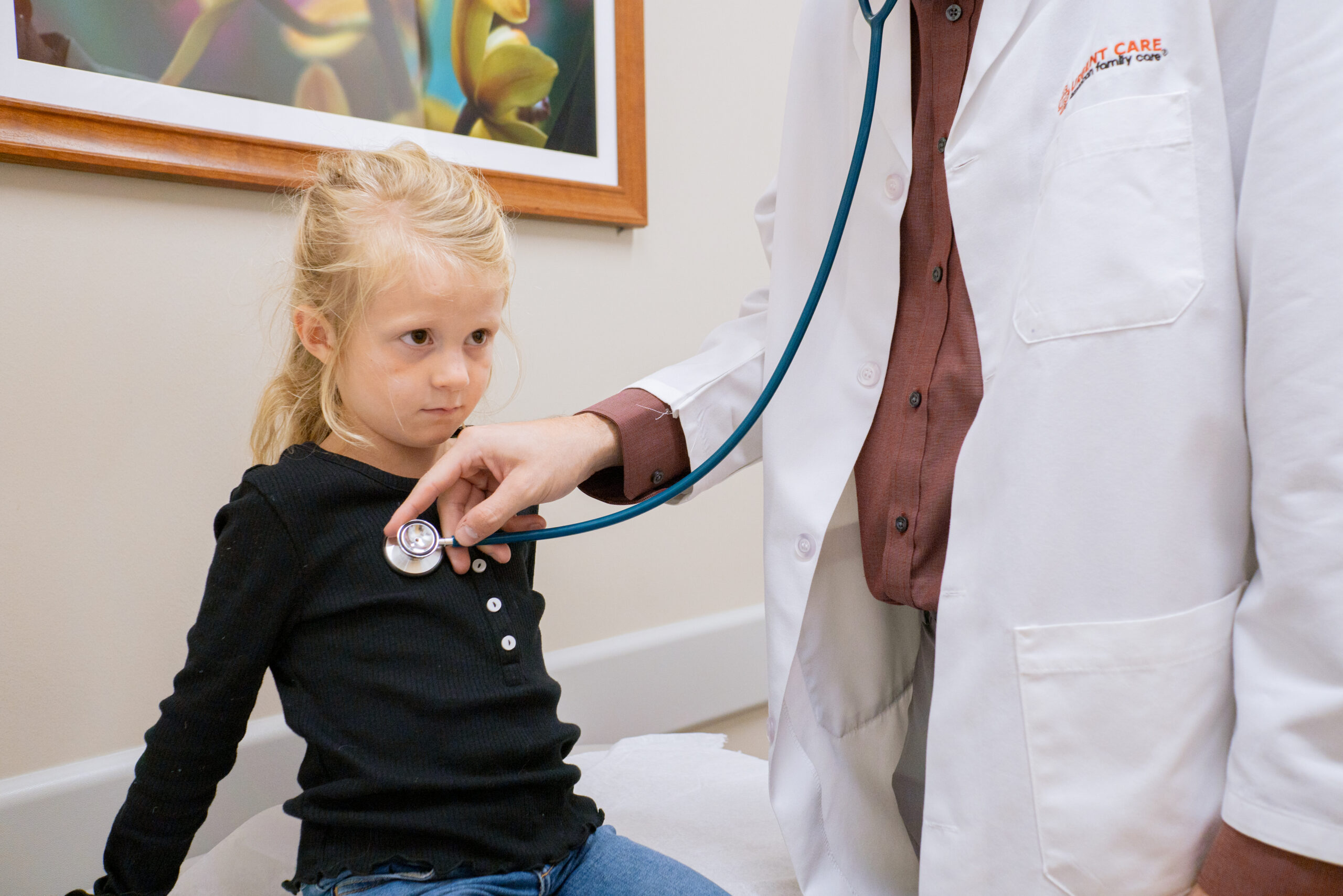 A medical professional listens to the heart of a young girl during an examination at AFC Urgent Care.